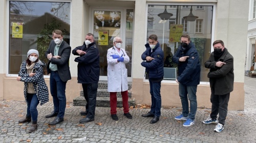 Oberbürgermeister Uwe Conradt, Wirtschaftsdezernent Tobias Raab, Verwaltungsdezernent Sascha Grimm und die Mitarbeiterinnen und Mitarbeiter stehen vor der Impfstation am St. Johanner Markt.