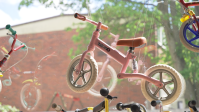 Kinderfahrrad Ein rosafarbenes Laufrad hängt in einem Schaufenster