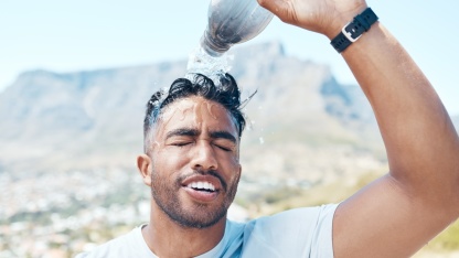 Tipps gegen Hitze Mann schüttet sich eine Flasche Wasser über den Kopf - Tipps gegen Hitze