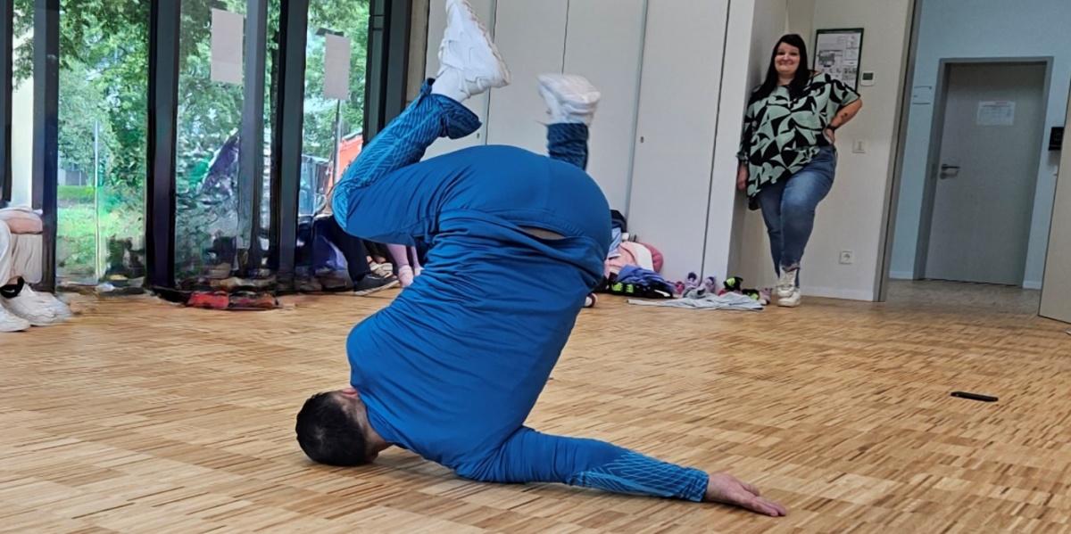 Breakdance mit Lil Ceng Breakdancer Gengis Ademoski in blauem Trainingsanzug macht eine Breakdance Bewegung