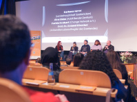 Podium beim Auftakt Demokratie leben 2025 Menschen auf einem Podium vor der Leinwand im Filmhaus Saarbrücken