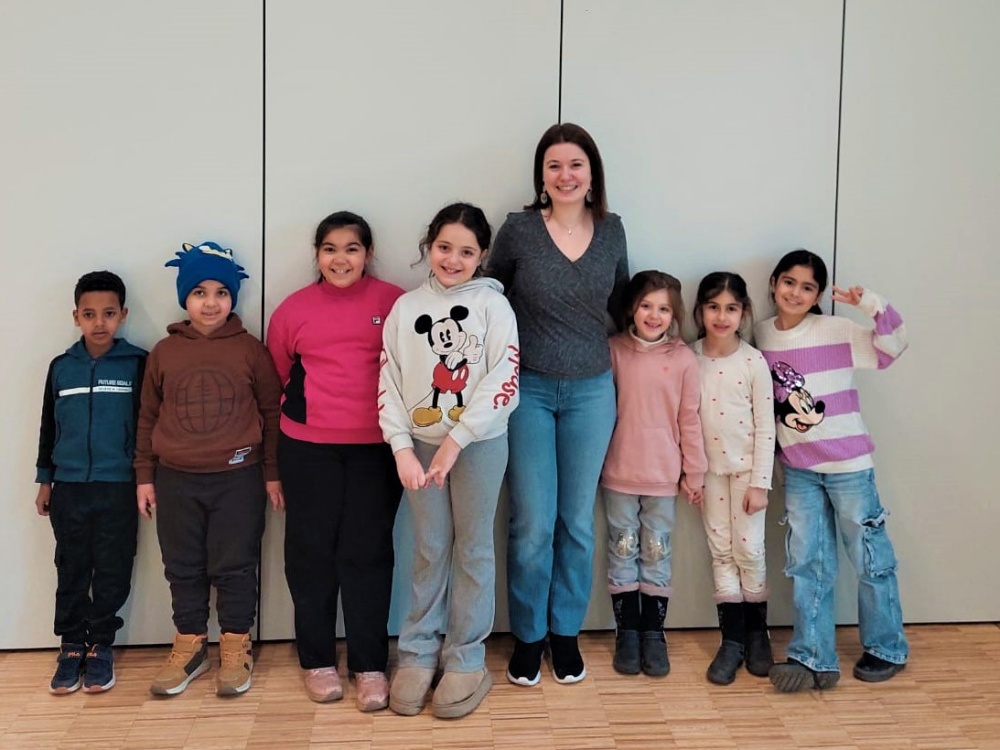 Bildungswerkstatt-Chor Kinder des Kinder-Chors der Bildungswerkstatt stehen in einer Reihe mit einer Frau
