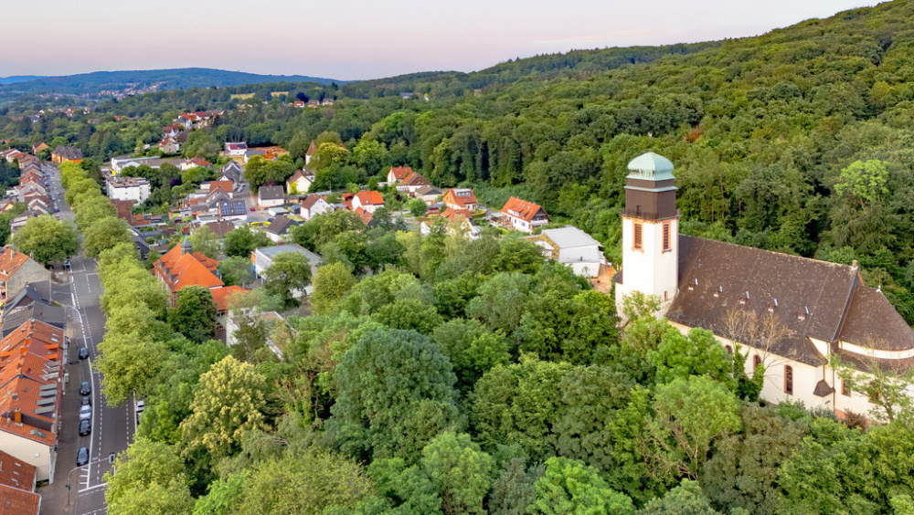 Sr. Hubertus Jägersfreude Kirche umgeben von Häusern und Wald