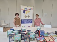 Zwei Team4Winners-Mitglieder stehen vor Roll-Up; Büchertisch Selbst.Los! Kulturstiftung; 