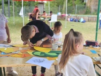 Kinder gestalten Kunstwerke während des Sprachcamps; Künstlerin leitet Kinder an