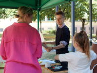 Kinder gestalten Kunstwerke während des Sprachcamps; Künstlerin leitet Kinder an