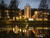 Nachtaufnahme von beleuchteten Gebäude und schwimmenden Sterne, die sich im Wasser spiegeln.