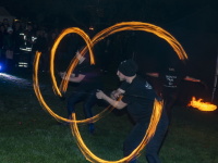 Feuerkünstler schwingen brennende Fackeln und zeichnen leuchtende Bögen vor staunendem Publikum.