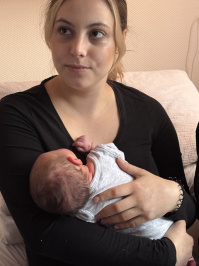 Mutter Felicitas Benoit hält Neujahrsbaby Malia im Arm und blickt zur Seite; das Baby liegt an ihrer Brust.