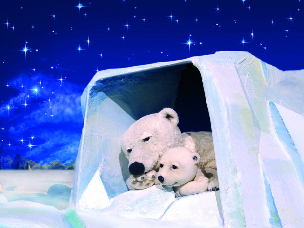 Szene aus "Der kleine Eisbär" Zwei Eisbären liegen in einer Eishöhle unter einem Sternenhimmel.