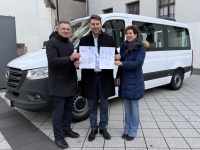 Oberbürgermeister Uwe Conradt steht mit zwei Mitgliedern des Vereins „Help4Ukraine e.V.“ vor dem Kleinbus im Innenhof des Rathauses St. Johann. Alle drei Personen halten ein Schriftstück in die Kamera.