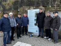 Eine Gruppe Menschen steht um eine Infotafel