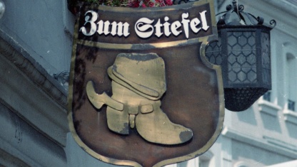 Detailaufnahme Gasthaus „Zum Stiefel“. Schild mit der Beschriftung "Zum Stiefel" und einem abgebildeten Stiefel an dem Gebäude des Gasthauses.