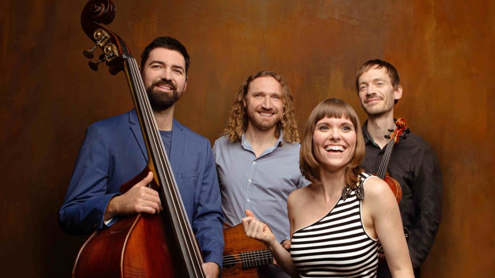 Marion & Sobo Band Vier Menschen stehen mit Instrumenten vor einer braunen Wand