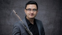Dante Montoya Mann in grauem Jakett mit Flöte in der hand
