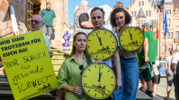 Menschen mit gelben Schildern vor dem Rathaus St. Johann