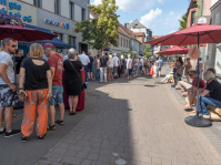 Eine belebte Straße mit Menschen die sich vor Ständen versammelt haben 
