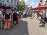 Eine belebte Straße mit Menschen die sich vor Ständen versammelt haben 