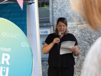 Eine Frau hält ein Mikrofon und hält eine Rede