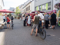 Sommerstraße 2026 Zwei Männer unterhalten sich in einer belebten Fußgängerstraße